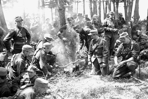 Velotruppen der Schweizer Armee 1914: Beim Kochen mit der Gamelle auf dem Feuer. Rechts wird mit dem Soldatenmesser geschnitzt.